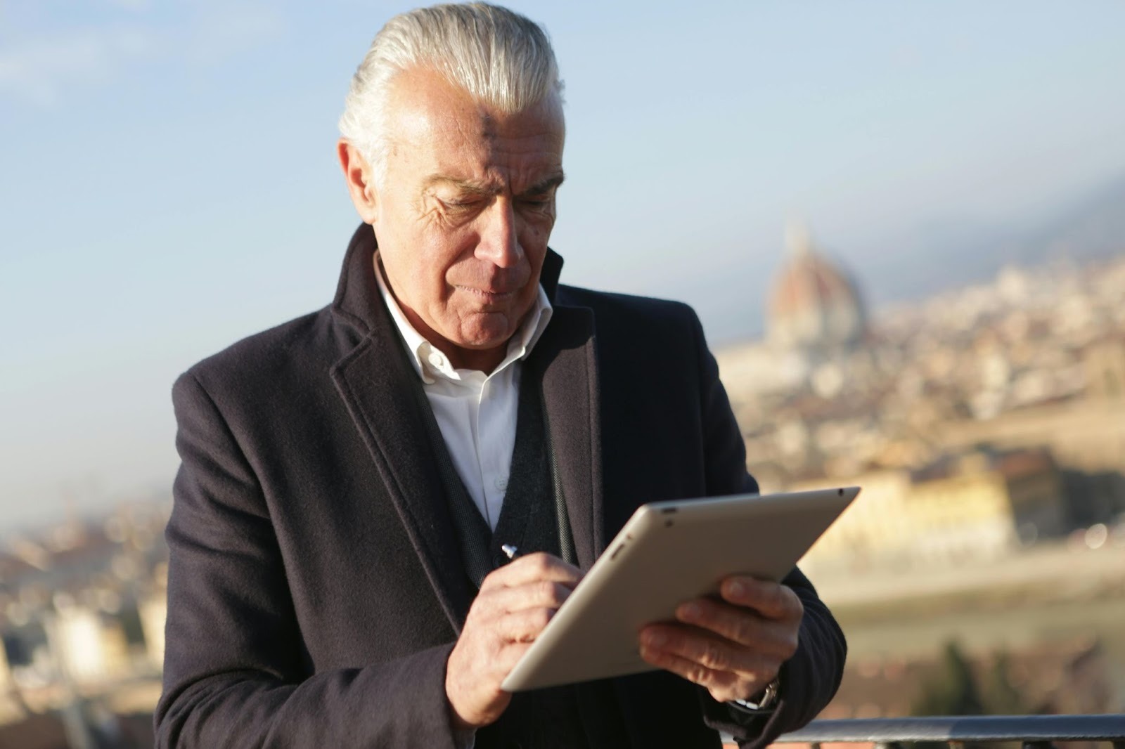 A mature man in a suit using a tablet