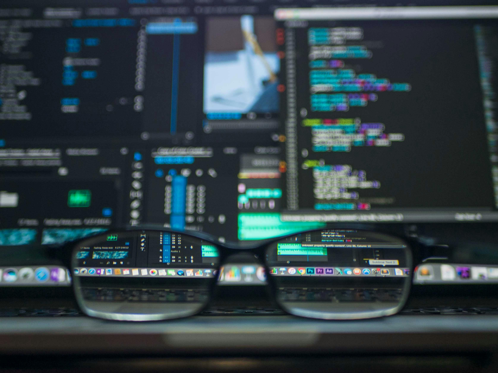 Eyeglasses resting in front of a computer screen displaying colorful code and developer tools