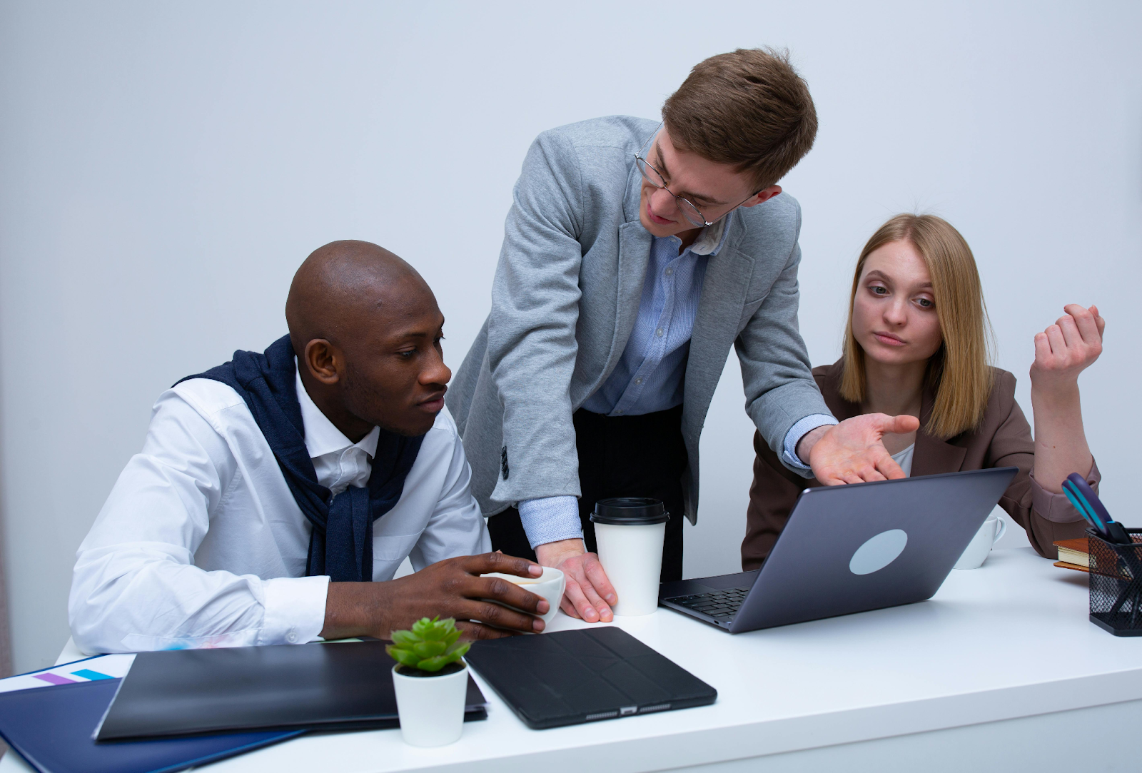 Three business professionals collaborating around a laptop in a modern office setting