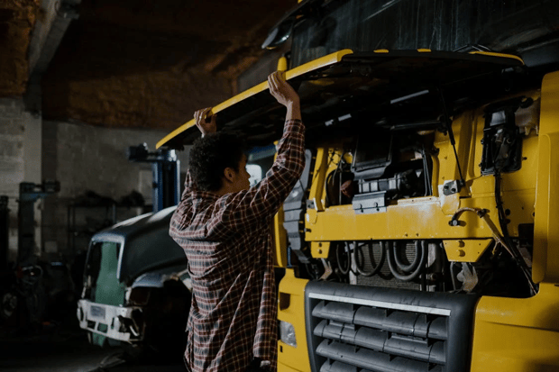 A mechanic inspects an open car truck bay showing the components.